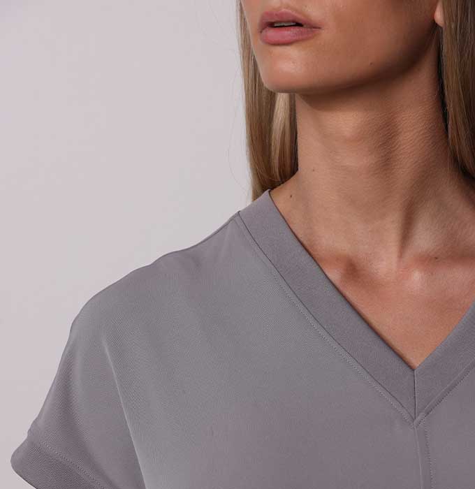 Close-up of a woman wearing a light gray short-sleeve V-neck top, showing the collar and shoulder area against a plain light background.